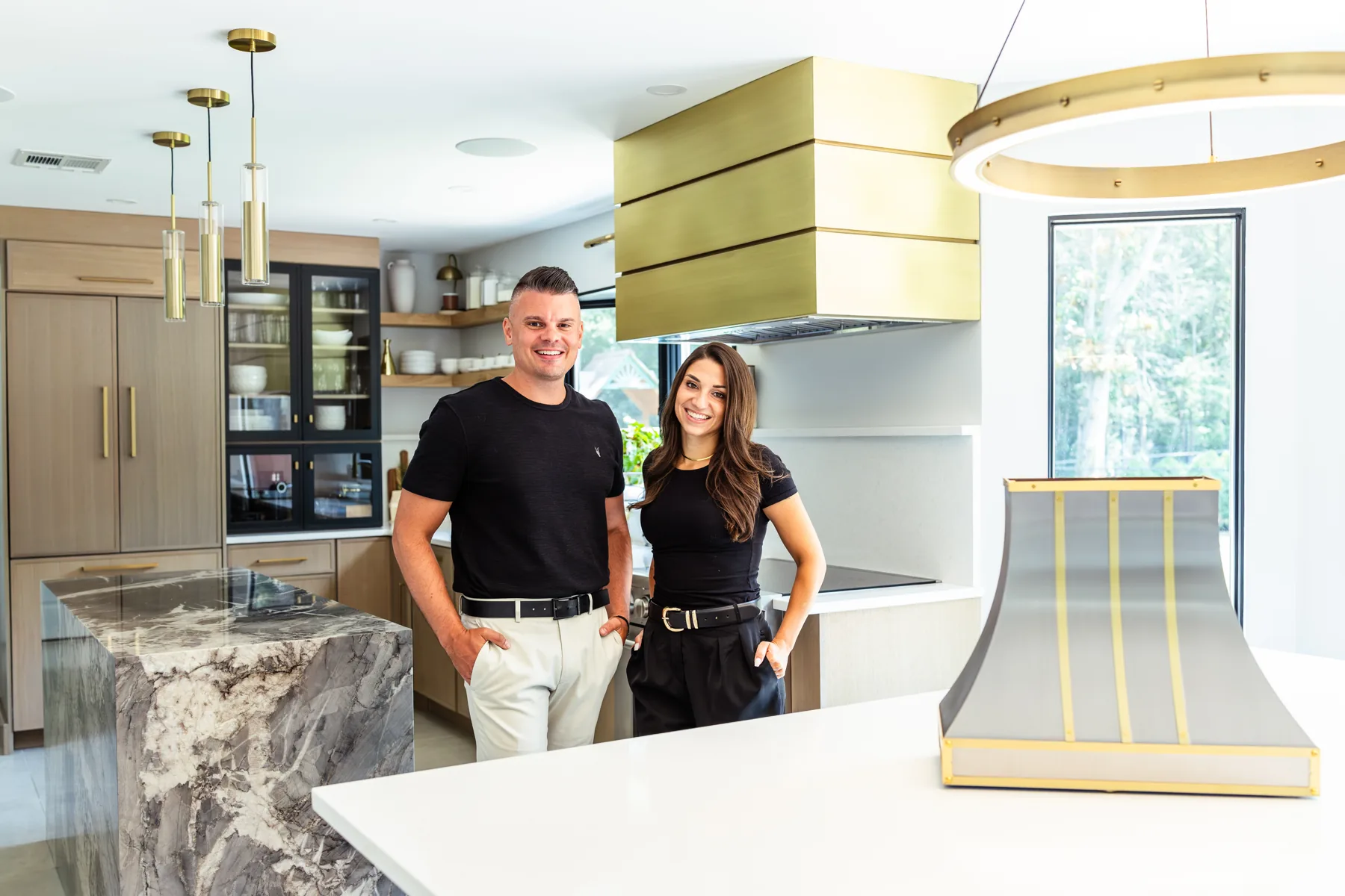 Brendan and Kaitlin Stoldt, Monarch's New York and New Jersey regional sales partners, in a kitchen with a brushed brass box range hood.
