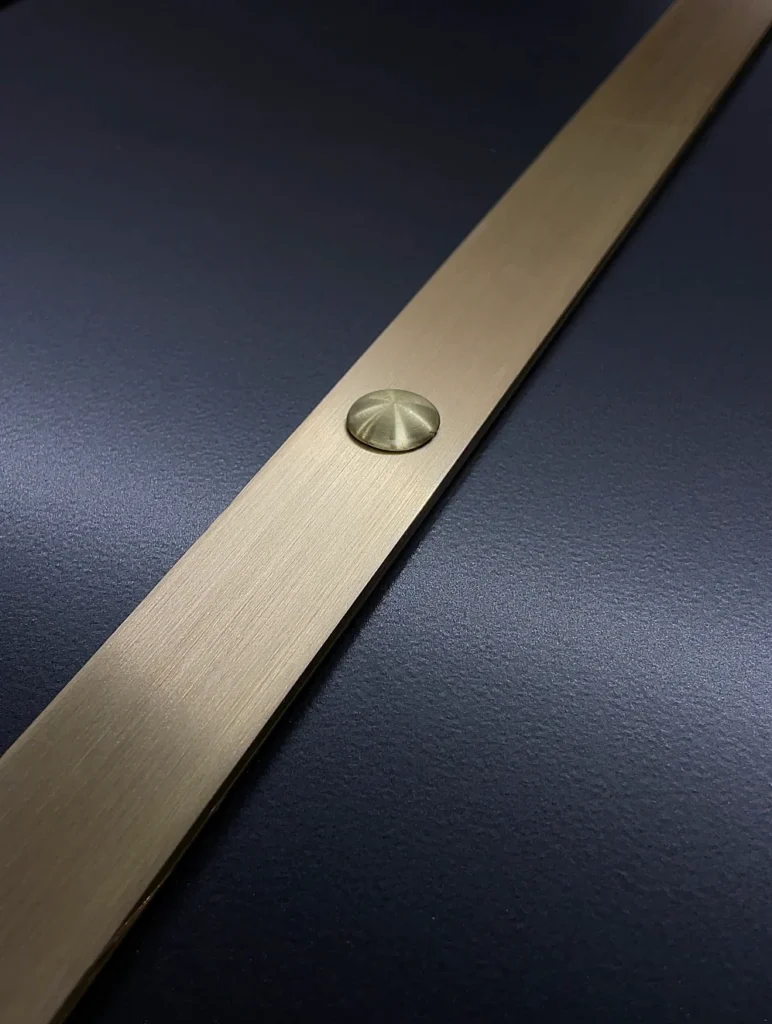 Black brushed brass metal finish detail on a custom range hood
